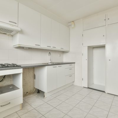 Kitchen with white furniture and tiled floor in the apartment of a residential building